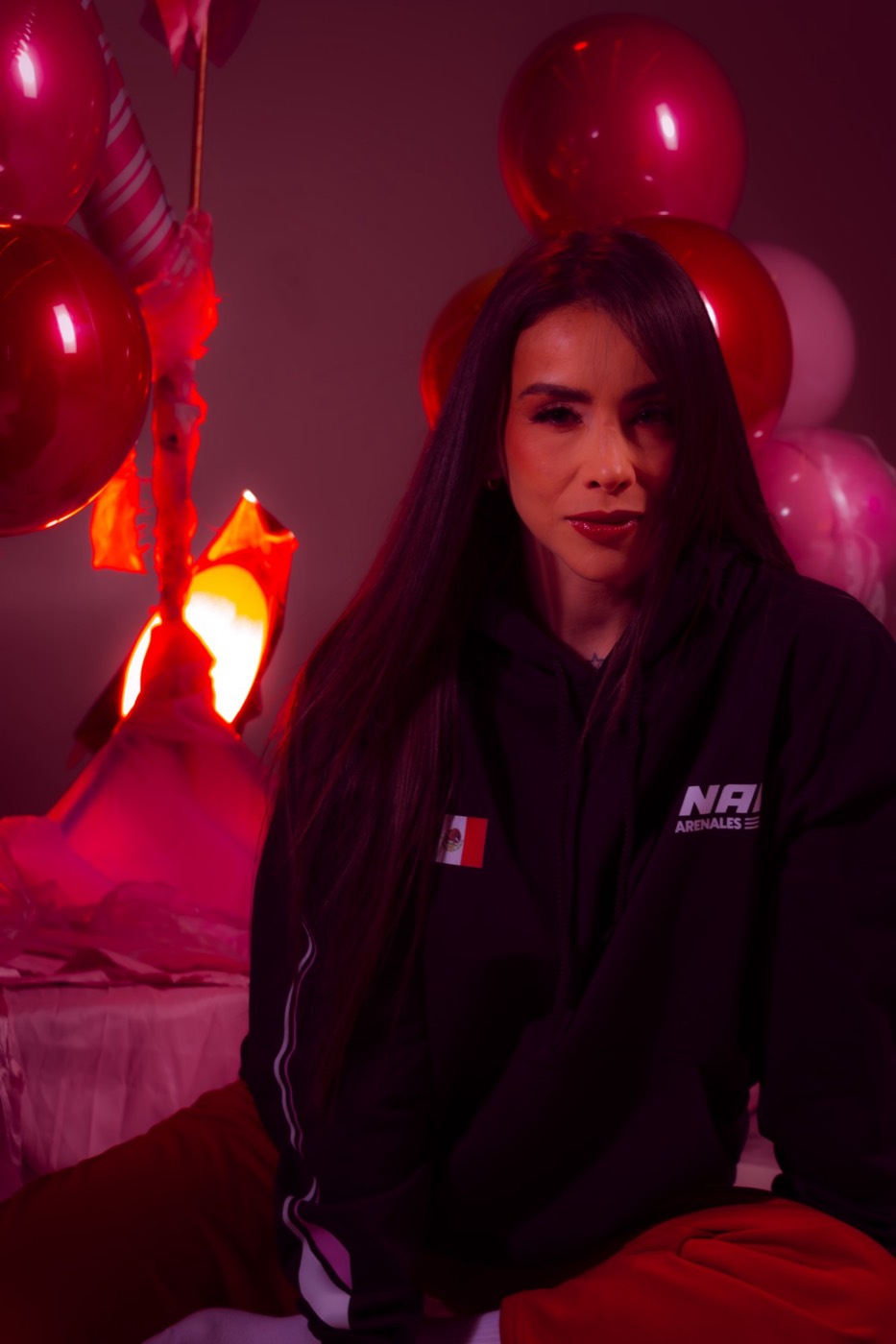 Retrato de Nana Arenales con hoodie negro y globos rojos